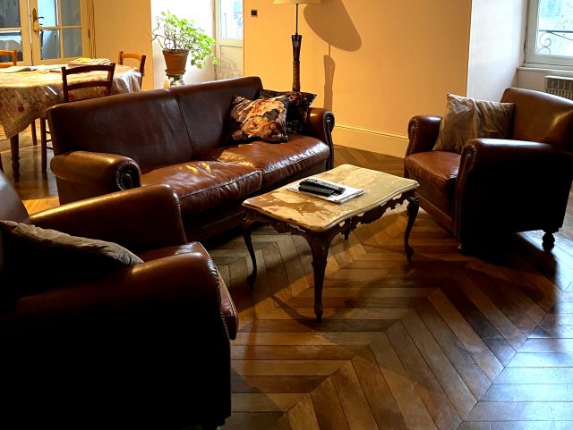 2 fauteuils Club et un canapé Club cuir marron Rochembeau dans un salon autour d'une table basse