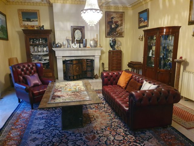 Salon Chesterfield fauteuil capitonné et canapé 3 places cuir rouge bordeaux marque Rochembeau devant une table basse