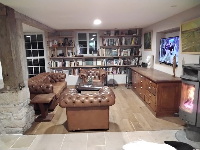 2 fauteuils Chesterfield capitonnés et un canapé Chesterfield cuir marron Rochembeau dans un salon autour d'une table basse