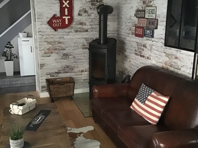 Canapé Club 3 places cuir marron foncé Rochembeau devant une table basse et tapis en peau de vache