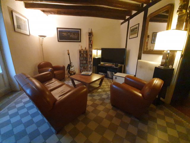 Salon Club : 2 fauteuils et un canapés table basse carrelage écran plat et poutres en bois