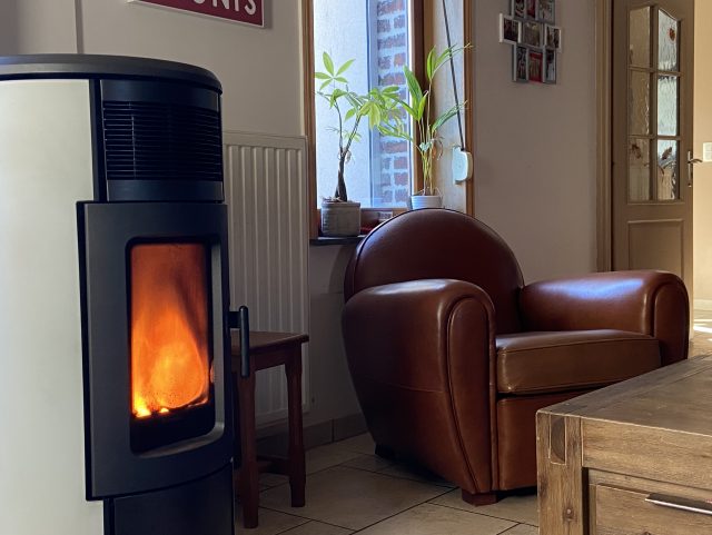 Fauteuil Club cuir marron à côté d'un poêle à bois et devant une table basse en bois