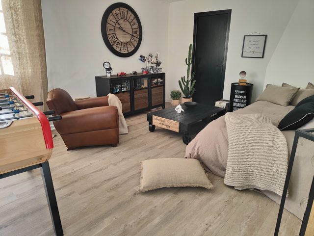 Fauteuil Club cuir Rochembeau dans une chambre avec babyfoot grande horloge et lit