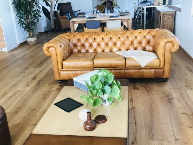 Canapé Chesterfield cuir miel jaune Rochembeau dans un salon devant une table basse en bois sur parquet bois