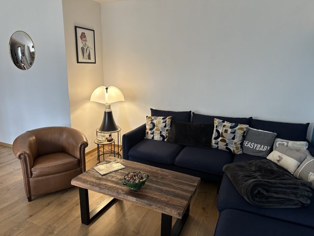 Fauteuil Club crapaud tonneau cuir marron dans un salon avec un canapé tissu devant une table basse