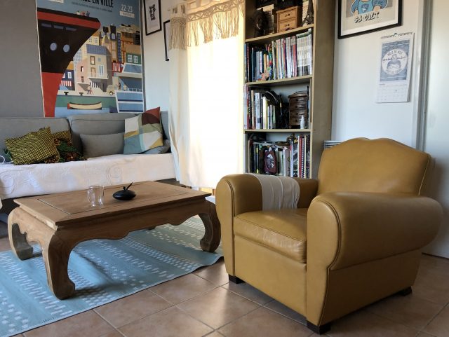 Fauteuil Club Moustache Rochembeau cuir jaune dans un salon avec table basse en bois, petite bibliothèque