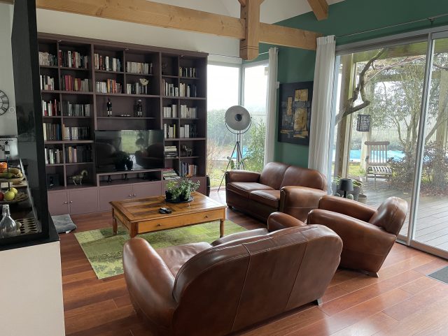 2 canapés Club et 1 fauteuil Club cuir marron foncé Rochembeau dans un salon, devant une table basse et une bibliothèque