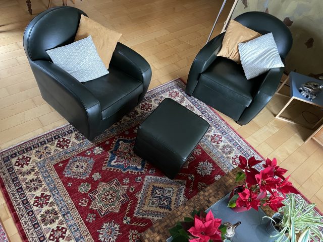 2 fauteuils Club cuir vert anglais et un pouf carré dans un salon et tapis