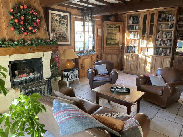 2 fauteuils Club et 1 canapé Club moustache marron Rochembeau dans un salon devant une table basse en bois et feu de cheminée