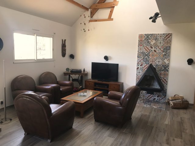 4 fauteuils Club cuir marron foncé Rochembeau devant une table basse bois sur parquet bois dans un salon